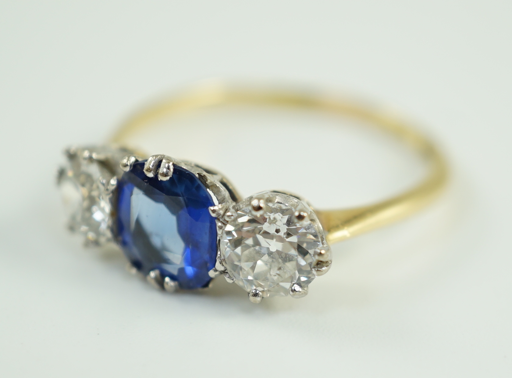 An 18ct gold, single stone oval cut sapphire and two stone round cut diamond set ring